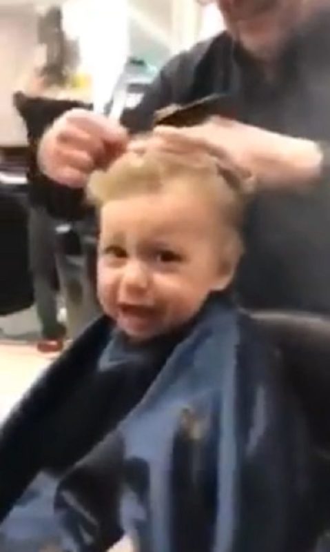 Barberos italianos comienzan a cantar para distraer a un niño asustado durante un corte de pelo.