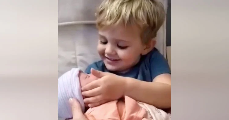 Niño pequeño sostiene a su nueva hermanita por primera vez, y es amor a primera vista.