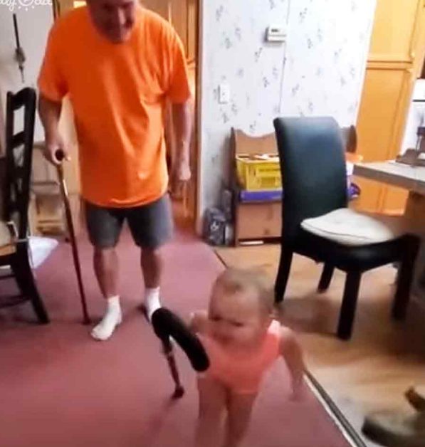 Una preciosa niña pequeña imita adorablemente el caminar de su abuelo.