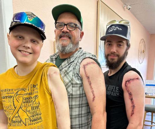 Una historia única, cicatrices compartidas: un padre y un hijo se sientan bajo la aguja del tatuador en un conmovedor gesto de respeto mutuo.