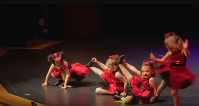 4 niñas pequeñas se alinean para su recital de baile navideño. Mantén tus ojos en la adorable con las gafas rosadas.