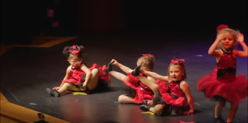 4 niñas pequeñas se alinean para su recital de baile navideño. Mantén tus ojos en la adorable con las gafas rosadas.