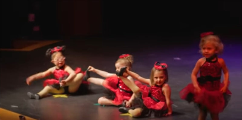 4 niñas pequeñas se alinean para su recital de baile navideño. Mantén tus ojos en la adorable con las gafas rosadas.