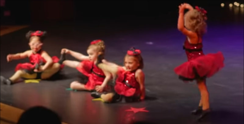 4 niñas pequeñas se alinean para su recital de baile navideño. Mantén tus ojos en la adorable con las gafas rosadas.