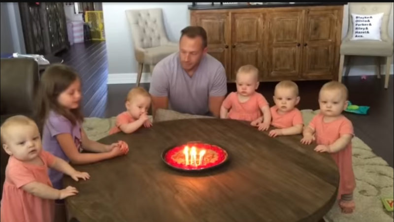 Las hijas desean feliz cumpleaños a su papá. Observa a los bebés mientras sopla las velas.
