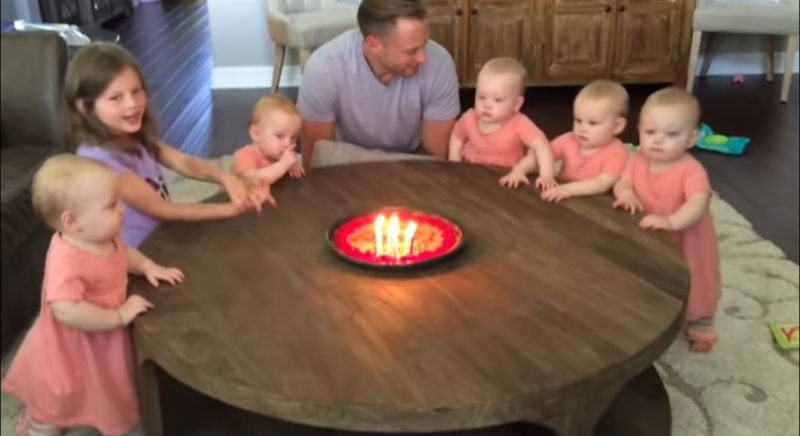 Las hijas desean feliz cumpleaños a su papá. Observa a los bebés mientras sopla las velas.