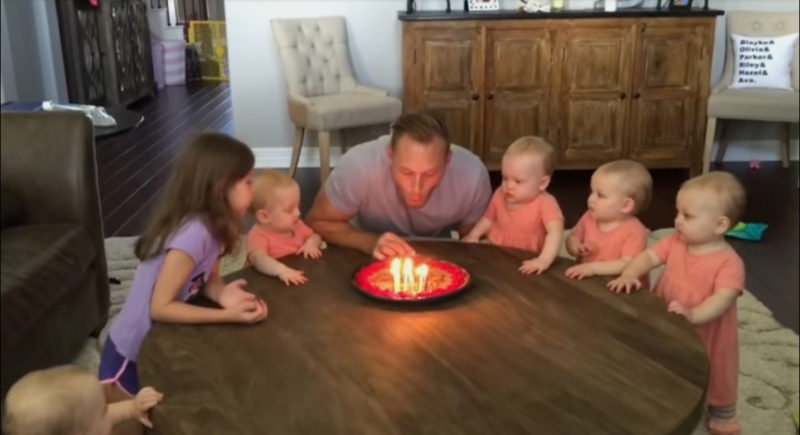 Las hijas desean feliz cumpleaños a su papá. Observa a los bebés mientras sopla las velas.
