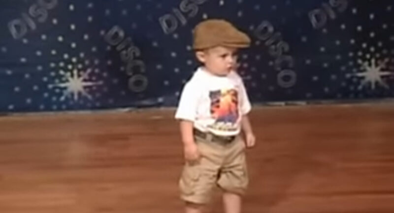 Un niño pequeño espera en el escenario para bailar: cuando comienza la música, el público se vuelve loco