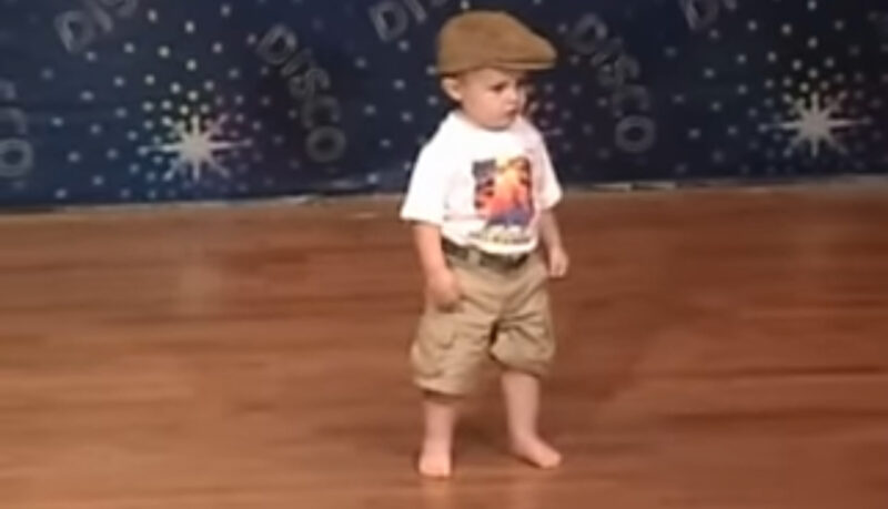 Un niño pequeño espera en el escenario para bailar: cuando comienza la música, el público se vuelve loco